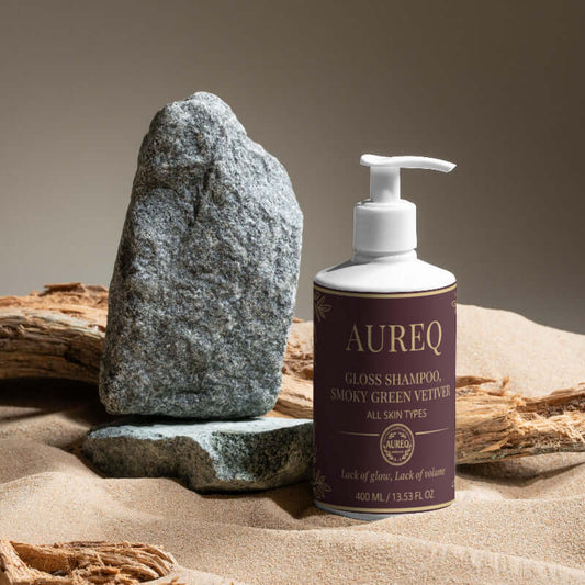 AUREQ Gloss Shampoo for smooth, shiny hair resting on natural elements, showcasing its refreshing formula.